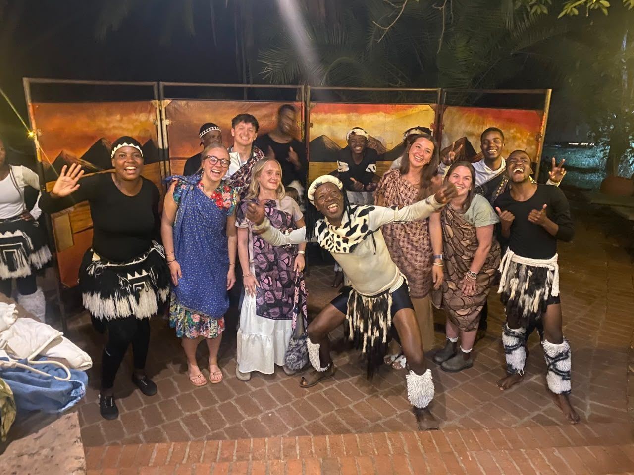 Guests and dancers laughing together at a drum show in Victoria Falls