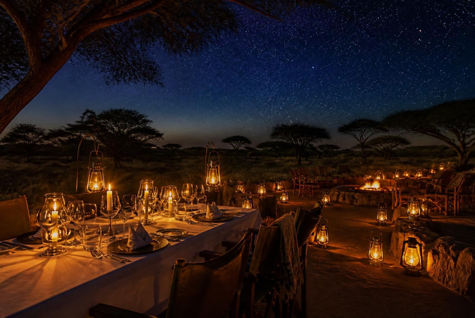 Fine dining table set under the stars with lanterns at a luxury safari camp