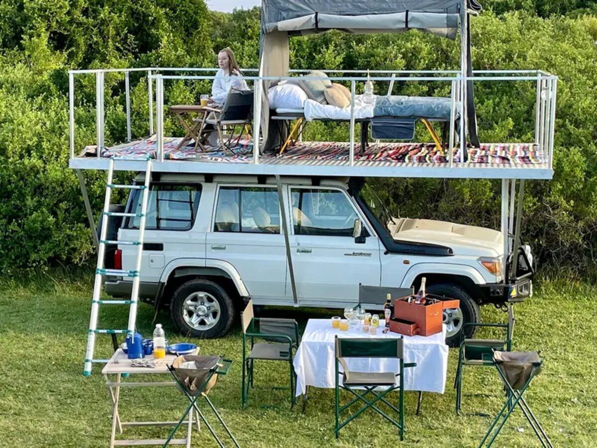 Land Cruiser with a rooftop tent and a breakfast table set up on the grass