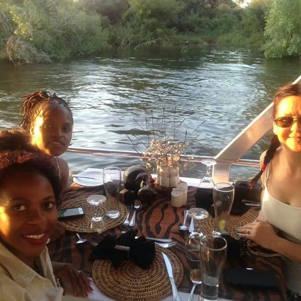 Guests at a decorated dinner table aboard a Zambezi cruise at sunset